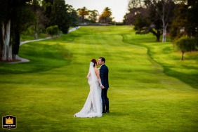 At The Club at Castlewood in Pleasanton, California, the bride and groom share a kiss, captured in a symmetrically framed wedding portrait on the tree-lined golf course.